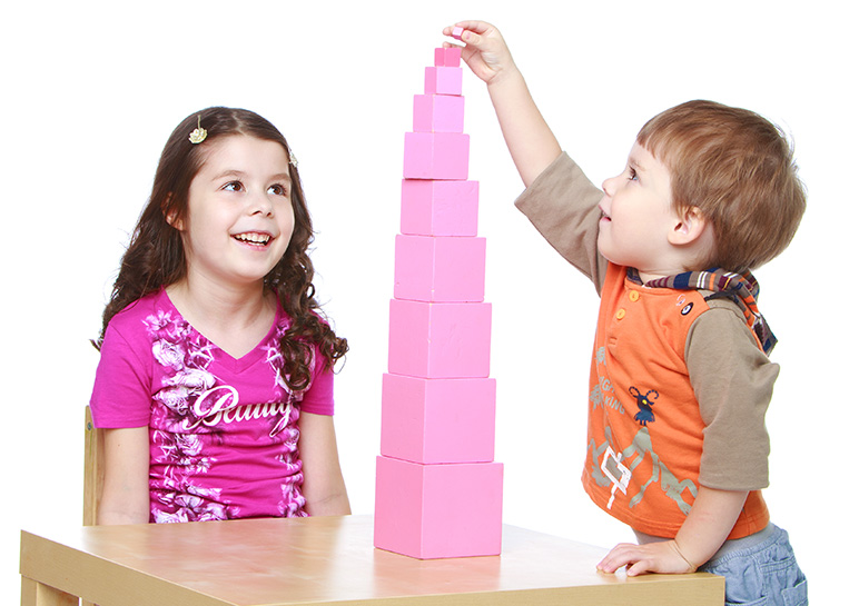 Two preschool age children construct a pink tower in a Montessori classroom. 